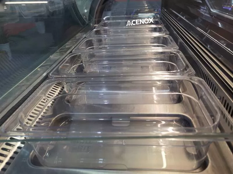 Cubetas transparentes de plástico instaladas en una vitrina para gelato